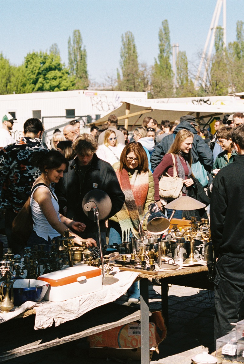 Belebter Stand mit Messing- und Kupferwaren auf einem Berliner Flohmarkt.